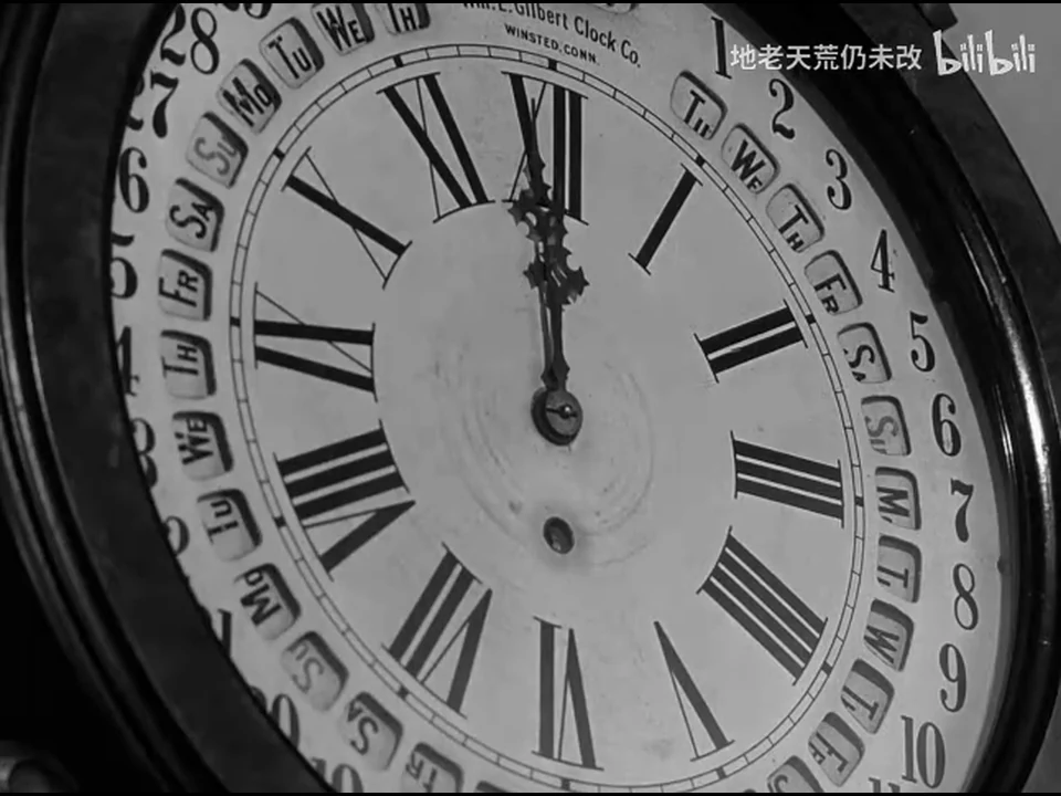 一只带日历环的圆钟占满画面，时针和分针在罗马数字十二处重合。