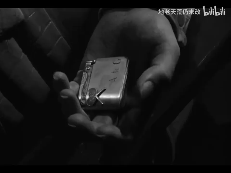Bruno 张开的手掌占据画面中央，矩形金属打火机横在掌中，正面可见“A to G”和交叉网球拍图案。